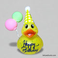 Yellow rubber duck with a birthday hat and balloons on a white background