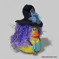 Decorative duck with witch costume including a hat, broom, and purple hair on a gray background.