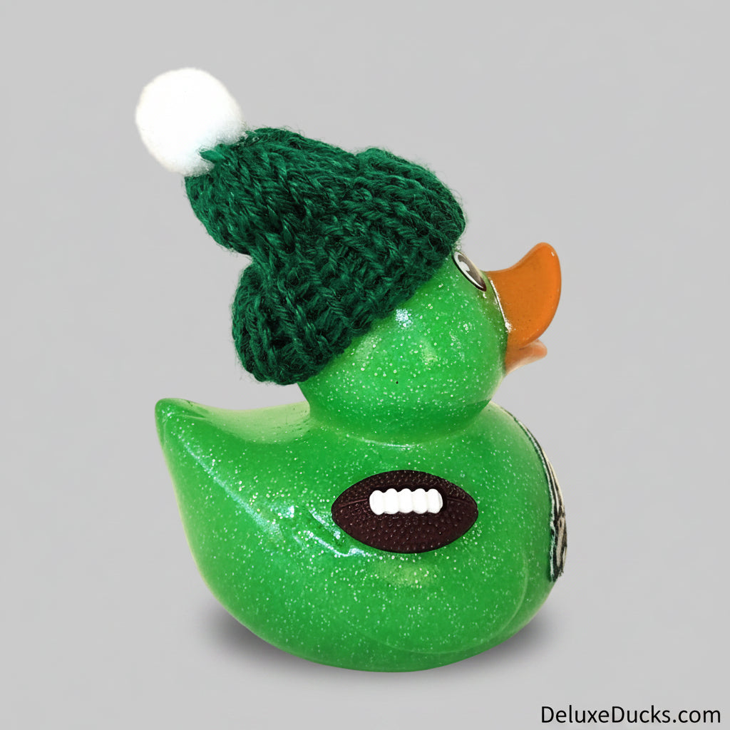 Green glittery rubber duck with a green knitted hat on a beige background