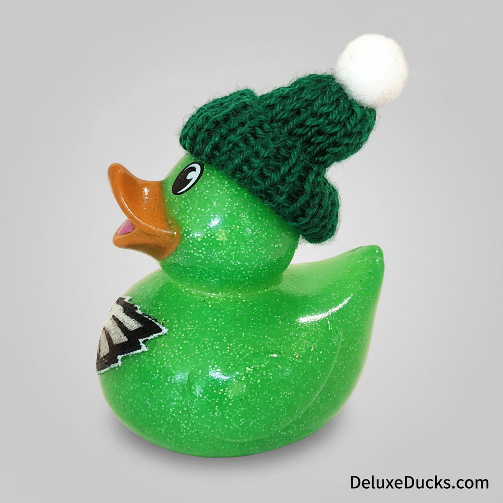 Green glittery rubber duck wearing a green knitted hat on a beige background