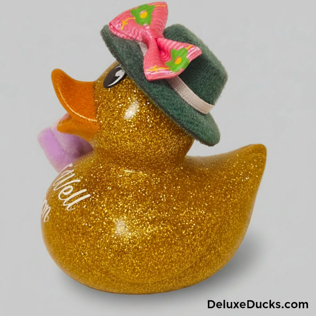Decorative duck with glittery gold body, pink bow, and green hat on a gray background