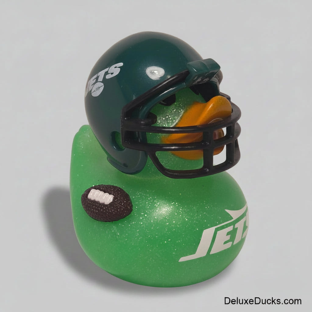 A green glittery rubber duck styled as a New York Jets duck, featuring a dark green football helmet with white and silver team logo details, a black faceguard, and an orange beak, sitting on a light beige background.