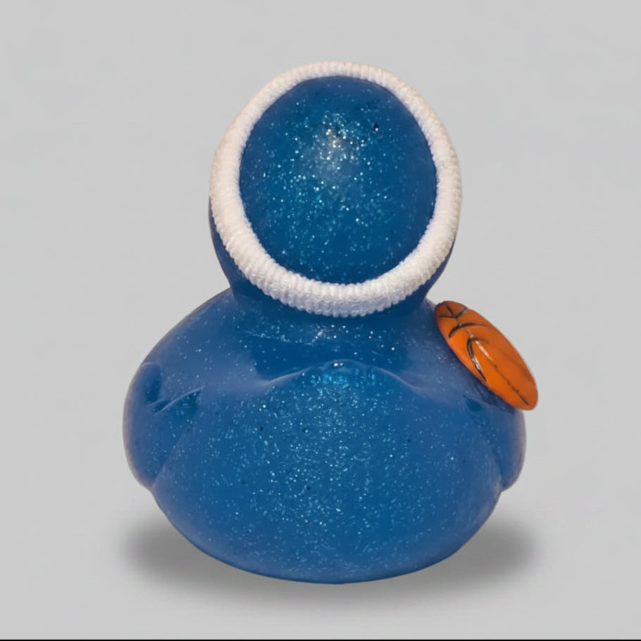 Blue glittery container with a white rim holding a small orange basketball on a beige background