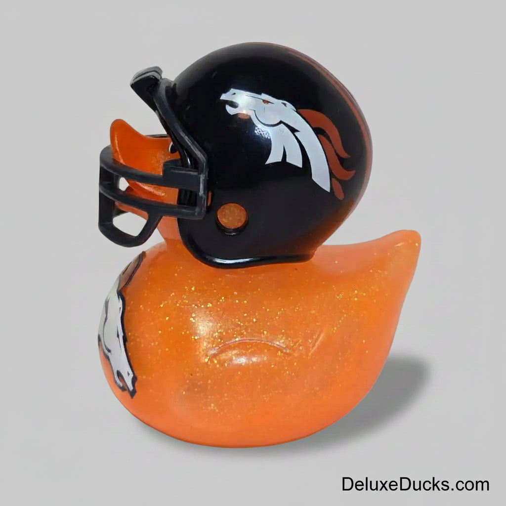 An orange glittery rubber duck featuring a black, orange, and white Denver Broncos helmet graphic, set against a plain light beige background.