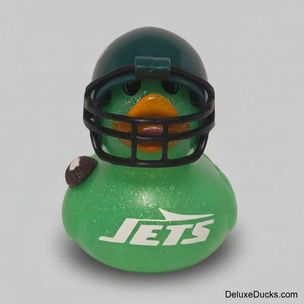 A green glittery rubber duck styled like a football player, wearing a dark green helmet with a black faceguard and an orange beak. The duck has 'JETS' printed in white on the front and a small football on its left side, set against a plain gray background.