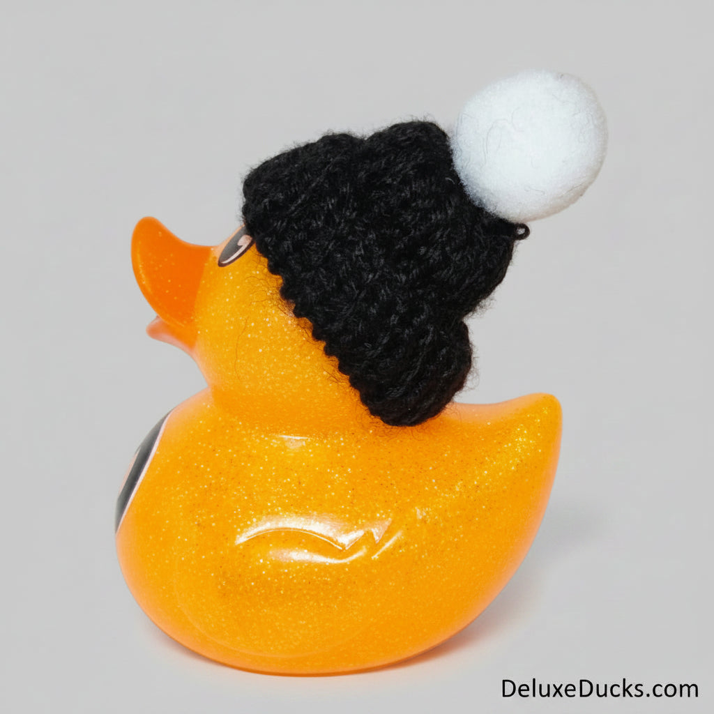Orange rubber duck wearing a black beanie with a white pom-pom on a light gray background