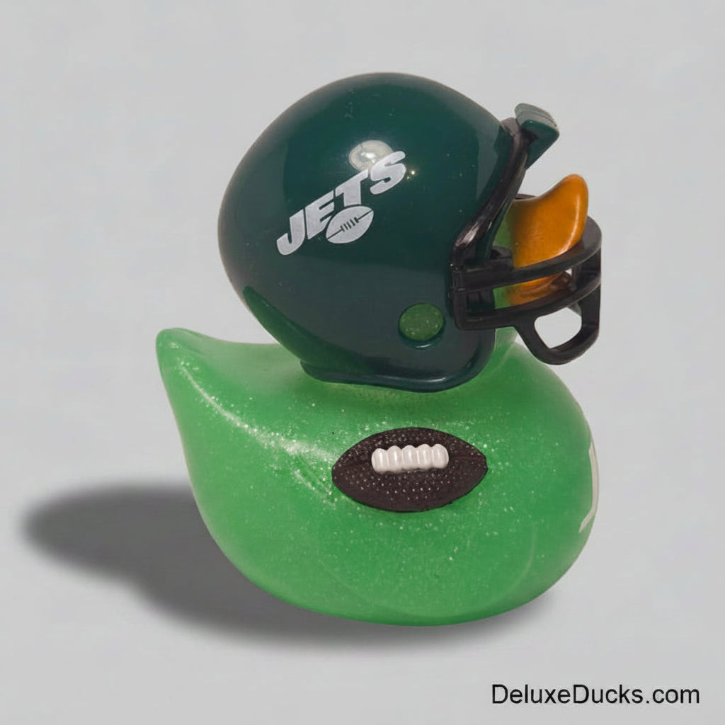 A green glittery rubber duck styled like a football team helmet, featuring a dark green helmet with white 'JETS' lettering, a black faceguard, and an orange ear cup, perched on a green duck body with a brown football detail.